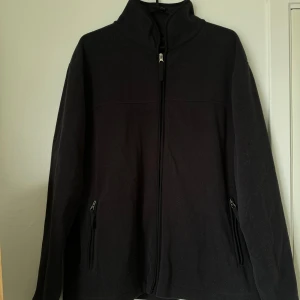 Svart fleecejacka från 157 - Säljer en svart fleecejacka från märket 157. Den har en dragkedja framtill och två praktiska fickor med dragkedjor. Perfekt för kyliga dagar och passar till både vardag och friluftsliv. Jackan är i storlek M och i bra skick.