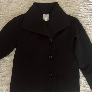 Svart kappa med stora knappar - Säljer en stilren svart kappa med stora knappar framtill. Den har en klassisk krage och är perfekt för både höst och vinter. Jackan är långärmad och har en normal passform, vilket gör den lätt att matcha med olika outfits. Perfekt för en chic och tidlös look! pris går att diskuteras💕💕