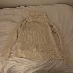 Vit stickad polotröja från 157 - Säljer en supermysig vit stickad polotröja från 157. Perfekt för kalla dagar med sin höga krage och långa ärmar. Tröjan är i storlek XS och passar perfekt för både höst och vinter. Den är i nyskick och redo att värma dig i stil!