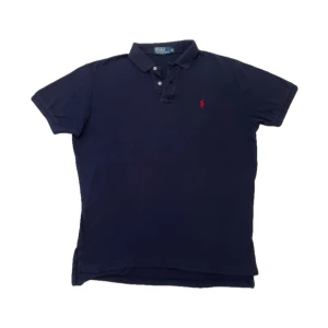 Ralph Lauren piké mörkblå  - En jättefin vintage mörkblå Ralph Lauren piké med röd loga i storlek M, den har inga defekter den är i mycket fint skick i 100 bomull🔥✅