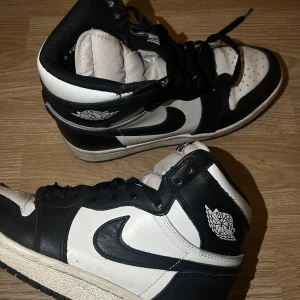 Svartvita Nike Air Jordans - Säljer ett par klassiska svartvita Nike Air Jordans. De har en snygg design med svart snörning och den ikoniska Nike-loggan på sidan. Perfekta för både vardag och fest!