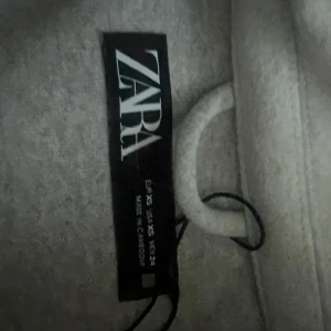 Beige jacka från Zara - Säljer en snygg beige jacka från Zara i storlek XS. Jackan har en stilren design med knappar framtill och två praktiska fickor med lock på bröstet. Perfekt för höst och vår!
