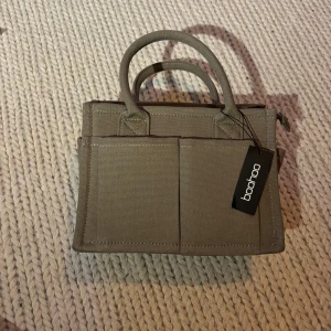 Canvas Front Pocket Tote bag  - En klassisk väska med ursprungs pris 550. Väskan har aldrig blivit använd och kommer från boohoo. Väskan är medelstor och färgen är gråbrun. 