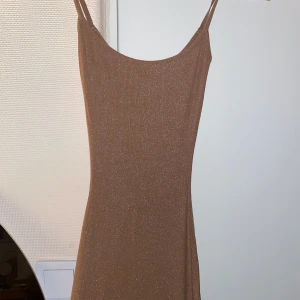 Skims, glittrig  - Säljer min beiga glittriga skims då jag har  två st.  Har bara använt den 2 gånger så den är som ny.  Den är i storlek Xs men väldigt stretchig! Klänningen är lång och ända ner till anklarna 