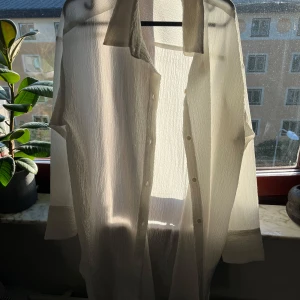 Vit långärmad skjorta - Oversized long-sleeved shirt dress in structured crepe fabric with rounded hem. Never been worn, didn’t get a chance to return it. It’s too big on me. Front buttoning & structured crepe fabric.