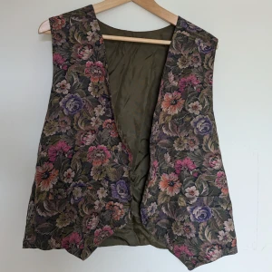 Blommig väst - Supersöt och fin! Säljer då den inte är min stil längre. Osäker på storleken, finns ingen lapp, men jag skulle gissa på L. Den är ca 40 cm bred och 60 cm lång. Skriv gärna vid frågor, och priset kan alltid diskuteras! 
