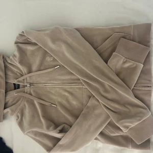 Juicy Couture kofta - Säljer denna beiga Juicy Couture koftan som inte kommer till någon användning längre. Koftan är i jättebra skick, knappt använd. Köpt i johnells. Skriv privat för mer bilder. Köptes för 1299 kr