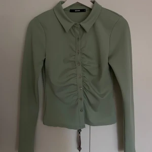 Mintgrön tröja från BikBok - Säljer en snygg mintgrön långärmad tröja från BikBok i storlek S. Tröjan har en fin rynkdetalj vid knäppningen. Perfekt för både vardag och fest! Oanvänd då jag aldrig provade den och när jag kom hem var den för liten💚