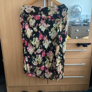 Blommig kjol  - En fin blommig kjol, med dragkedja på sidan. Där är volanger på kjolen. 