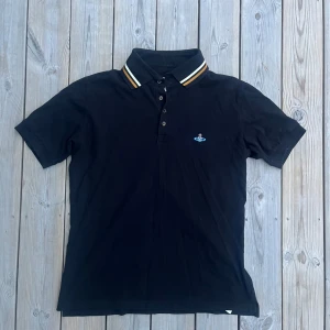 Svart pikétröja från Vivienne Westwood - Säljer en snygg svart pikétröja från Vivienne Westwood. Fullt äkta, vintage modell. Står XL, men är runt M i verkligheten.