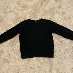 Polo Ralph lauren tröja  - Säljer en svart polo Ralph lauren tröja med ett rött märke då den är för liten. Tröjan är hel men ganska använd.
