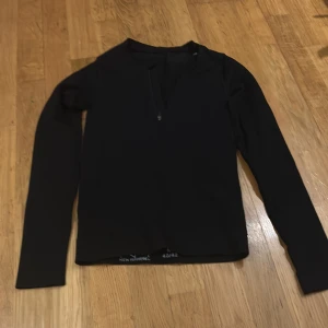 Svart långärmad tröja från New Apparel - Säljer en stilren svart långärmad tröja från New Apparel i storlek M (40/42). Tröjan har en dragkedja framtill och är perfekt för både vardag och träning. Materialet känns mjukt och bekvämt mot huden. Passar bra till höst- och vårsäsongen.