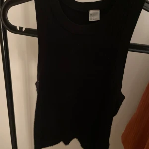 Svart ribbad linnetopp - Snygg svart ribbad linnetopp i storlek S. Perfekt för både vardag och festliga tillfällen. Den är ärmlös och har en tight passform som framhäver figuren. Ett måste i garderoben för alla säsonger!