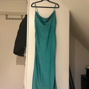 Turkos långklänning från Stradivarius - Säljer en elegant turkos långklänning från Stradivarius i sidenliknande material. Klänningen har smala axelband och en diskret slits som ger en snygg detalj. Perfekt för sommarens fester eller en speciell kväll. Använd få gånger och i mycket bra skick!