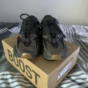 Yeezy 700 utility black - KVITTO HITTAT! Yeezy Boost 700 i färgen ”Utility black”. Skorna är i gott skick med en liten skada på sulan och på insida häl på högra skon se sista bild. Köptes från plugmeplease i Stockholm 2020. 