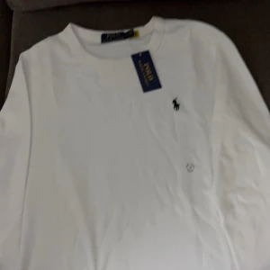 Vit t-shirt från Ralph Lauren - Säljer en klassisk vit t-shirt från Ralph Lauren i nytt skick. Den har en liten broderad logga på bröstet och är gjord i mjuk bomull. Perfekt för en stilren och avslappnad look. Passar till både vardag och fest!
