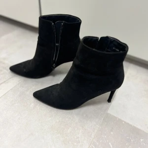 Svarta mocka boots med klack - Snygga svarta boots i mocka med spetsig tå och smal klack. Använda ett fåtal gånger, klacken har en liten defekt (se bild) i övrigt är de i topp skick. Storlek 37. Pris 400kr och kan diskuteras 