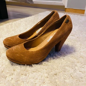 Bruna pumps från Kickers - Snygga bruna pumps från Kickers i mocka med en bekväm klack. Stl 39!De har ett diskret randigt mönster och en rundad tå. Perfekta för både vardag och fest! 🥿