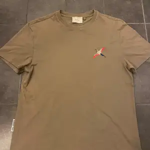 Säljer en snygg beige t-shirt från Axel Arigato i mycket bra skick. Den har en cool broderad fågel i rött, blått och grått på bröstet. Perfekt för en avslappnad stil! 🕊️Stolek m herr. Bra skick använd några gånger.  nypris 1099 köpt på nk i Stockholm. Priset är ganska fast. Går att pruta. Bara att skriva ifall ni har frågor! 