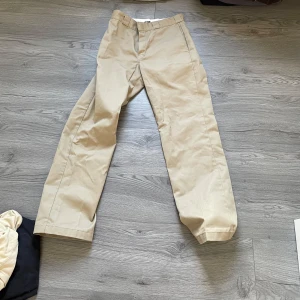Beige byxor från Dickies - Säljer ett par klassiska beige Dickies 874 Original Fit byxor. De har en rak passform och är perfekta för både vardag och arbete. Byxorna är i nyskick bara använda några gånger. Perfekta för höst och vår!