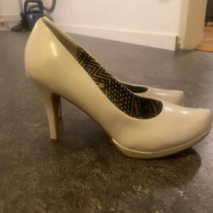 Vita  pumps från Chilli Shoes - Säljer ett par vita pumps från Chilli Shoes i storlek 40. Skorna har en klassisk design med spetsig tå och klack, perfekt för festliga tillfällen.