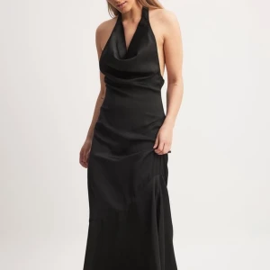 Svart långklänning med öppen rygg och halterneck - Svart maxi långklänning i satin med halterneck och öppen rygg. Har två stycken, en i storlek 38 och en i 40. 250 kr styck. Aldrig använda med lappar kvar.