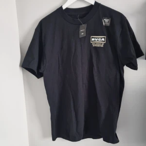 Svart t-shirt från RVCA - Säljer en svart t-shirt från RVCA i 100% bomull. Den har trycket 'Balance of Opposites' både fram och bak. Perfekt för en casual look och passar till alla tillfällen. T-shirten är i nytt skick och har en normal passform.