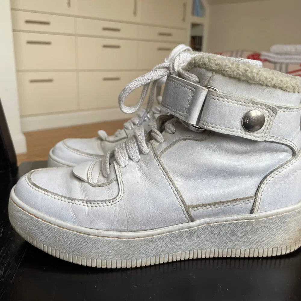 Säljer ett par vita lädersneakers från Hope i bra skick! De har snörning och en justerbar ankelrem med knapp. Insidan är fodrad med teddymaterial och innersulan är av läder. Supersköna och grymt snygga! Sparsmakat använda.. Skor.