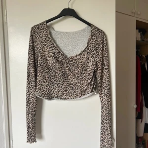 Leopardmönstrad croppad topp - Snygg leopardmönstrad croppad topp med långa ärmar. Perfekt för en utekväll eller när du vill känna dig extra trendig. Materialet är mjukt och stretchigt för en bekväm passform.