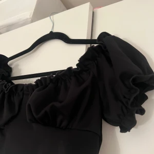 Svart offshoulder topp från NLY One - Säljer en snygg svart offshoulder topp från NLY One. Toppen har puffiga ärmar och en elastisk kant som ger en fin passform. Perfekt för att styla med både kjol och byxor. 🖤