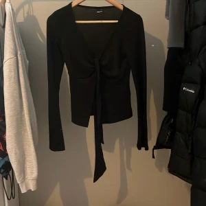 Svart knyttröja från Gina Tricot - Snygg svart tröja från Gina Tricot med knytning framtill. Perfekt för en stilren look. Tröjan har långa ärmar och en elegant design som passar till många tillfällen.