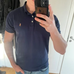 Mörkblå pikétröja från Ralph Lauren - Snygg mörkblå pikétröja från Ralph Lauren i storlek M/L fick i present men säljare pga att den  är för liten! Vid frågor och funderingar skriv