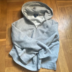 Grå zip Ralph lauren  - Säljer en snygg zip hoodie från Ralph Lauren, svin snygg till våren och även najs att ha under jackan. Skulle rekommendera folk som e runt 170-177. Använt den en gång.