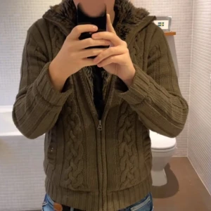 Cardigan - Säljer en mysig brun stickad tröja. Insidan är fodrad med ett rutigt mönster. Perfekt för kyliga dagar!