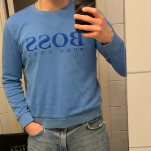Blå tröja från Hugo Boss - Säljer en stilren blå tröja från Hugo Boss med deras logga tryckt på framsidan. Tröjan har en slim fit passform och långa ärmar, perfekt för en casual look. Passar bra till jeans eller chinos. Hör av dig vid intresse! 💙 ( priset går att diskuteras) 