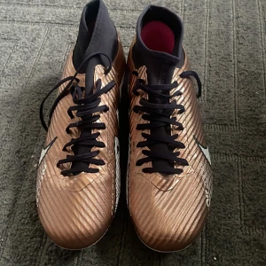 Nike fotbollsskor - Säljer ett par bronsfärgade Nike Mercurial superfly Academy, nypris 1100!!!. Fungerar på både konstgräs och naturgräs. Endast använda 2 gånger! Mycket bra skick! Storlek 42,5, UK 8. Lägre pris kan diskuteras.
