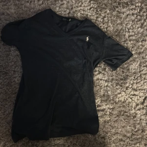 Svart t-shirt från Polo Ralph Lauren - Snygg svart t-shirt från Polo Ralph Lauren med v-ringning och en liten broderad logga på bröstet. Perfekt för en stilren look. Perfekt för sommarn fråga för fler bilder 