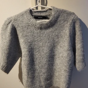 Grå stickad tröja från Vero Moda - Mysig grå stickad tröja från Vero Moda med trekvartsärm. Perfekt för kyliga dagar och ger en stilren look. Tröjan har en rund halsringning och är gjord i ett mjukt material som känns skönt mot huden. Ny pris 449:-