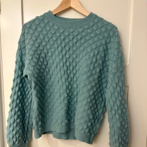 Blå stickad tröja från E-woman - Mysig blå stickad tröja från E-woman med ett unikt mönster. Perfekt för kyliga dagar med sin bekväma passform och långa ärmar. En stilren och varm tröja för alla tillfällen.