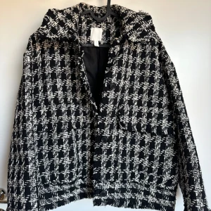 Svart/vit  jacka H&M - Snygg svart och vit rutig jacka med knappar framtill. Jackan har en klassisk krage och en stilren design som passar perfekt för höst och vår. Den är långärmad och har en bekväm passform. Storlek S