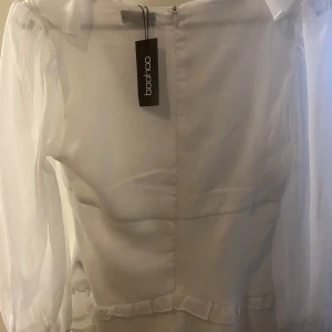 En vit blus - Jag säljer just nu en jättesöt vit blus i helt nyskick. Vilket även syns på att lappen sitter kvar. Säljs pga fel storlek. Säljer för 50kr + frakt.