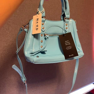 Helt ny nakd väska! - Helt ny med prislappen kvar på. Blå med fina detaljer, säljer pga används ej. Nypris på den var 399 kr säljer för 250 kr. Priset går alltid att diskutera! 💙