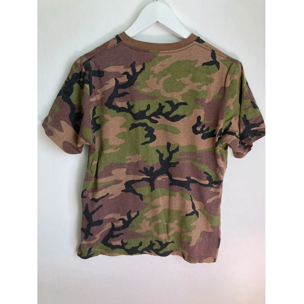 Kamouflagemönstrad bomulls t-shirt med Vans tryck. Väl använt skick. Mått i cm: bröstvidd 46; axelbredd 40; längd fram från axeln 57,5; ärmlängd 20.. T-shirts.