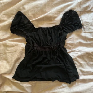 Svart topp - Söt svart topp med knytning i mesh material. Säljer då den ej kommer till användning.