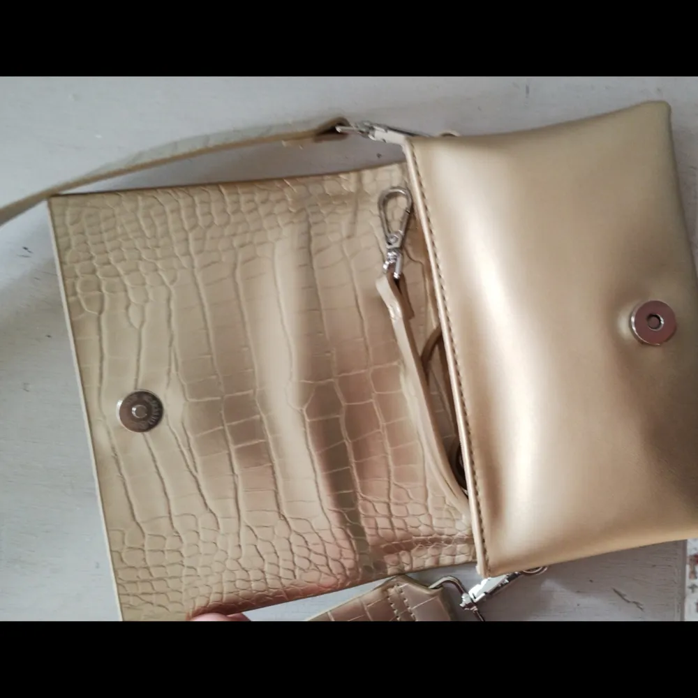 Fin väska från Carin Wester i fin guldfärg , finns ett tjockare och ett smalare axelband man kan använda , helt ny , nypris 499 kr . Väskor.