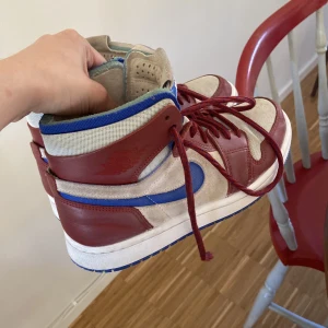 Air jordan 1 zoom air comfort - St 38. Vinröda, blåa och vita. Väl använda så det vita är lite skitigt men har försökt rengöra så gott som möjligt. Plasten på snörändena är sönder på båda skorna men man kan fortfarande trä dem genom alla ögglor.