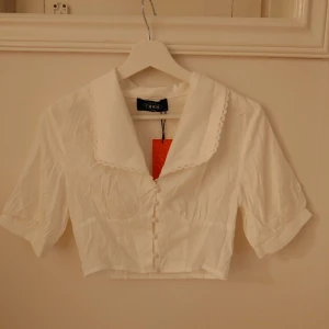 Vit crop top - Säljer för att den var för liten. Vit crop top skjorta från Cider. Nyskick, endast testad en gång  Storlek:XS (står XS men skulle gissa på att den är XXS) 