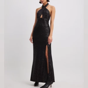 Klänning med halterneck och nyckelhålsdetalj - Klänningen är aldrig använd och är i ursprunglig förpackning. Den är av ett paljettmaterial som har en sidoslits samt en djup rygg💞  Nypris: 799kr