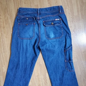 Flared jeans med röda sömmar från Diesel - Ett par flared dieseljeans med röda sömmar och diverse fickor som är riktigt bekväma.