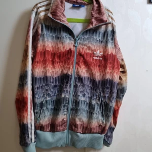 adidas zipup - Hej, säljer min färgglada adidas jacka! Den har nästan aldrig blivit andvänd, den har ett adidas märke bak på ryggen och har " fjäder" mönster med olika färger❤️